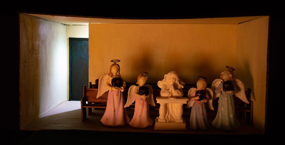 Na young Yi. God is Good. Sculpture (Cardboard, LED Bulb, Air Dry Clay, UV Flashlight, UV Pens, and Angel Figurines), 8” x 16.5” x 11.5”, 2021