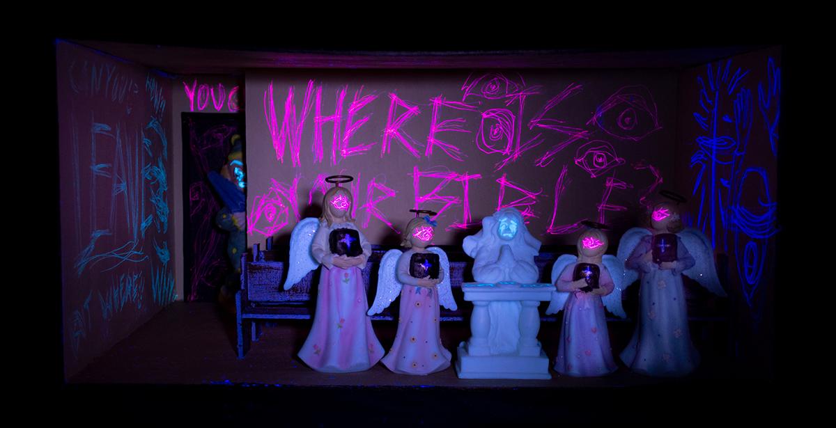 Na young Yi. God is? Sculpture (Cardboard, LED Bulb, Air Dry Clay, UV Flashlight, UV Pens, and Angel Figurines), 8” x 16.5” x 11.5”, 2021